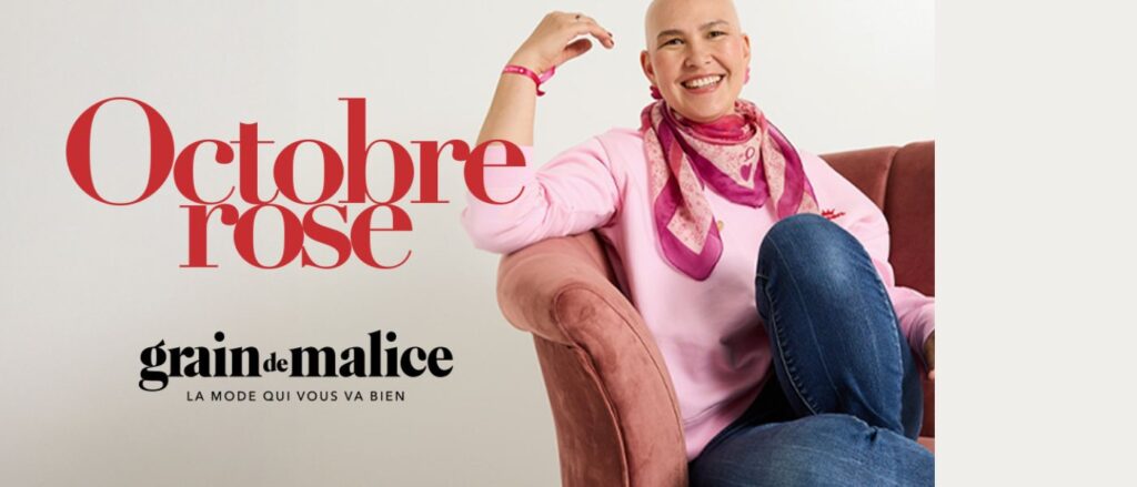 Femme souriante en pull rose et foulard rose assise dans un fauteuil, symbole de solidarité et d’espoir pour Octobre Rose. Campagne Grain de Malice engagée pour soutenir la recherche contre le cancer du sein.