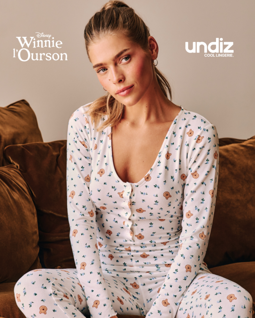 Femme assise sur un canapé portant un pyjama blanc à motifs Winnie l’Ourson